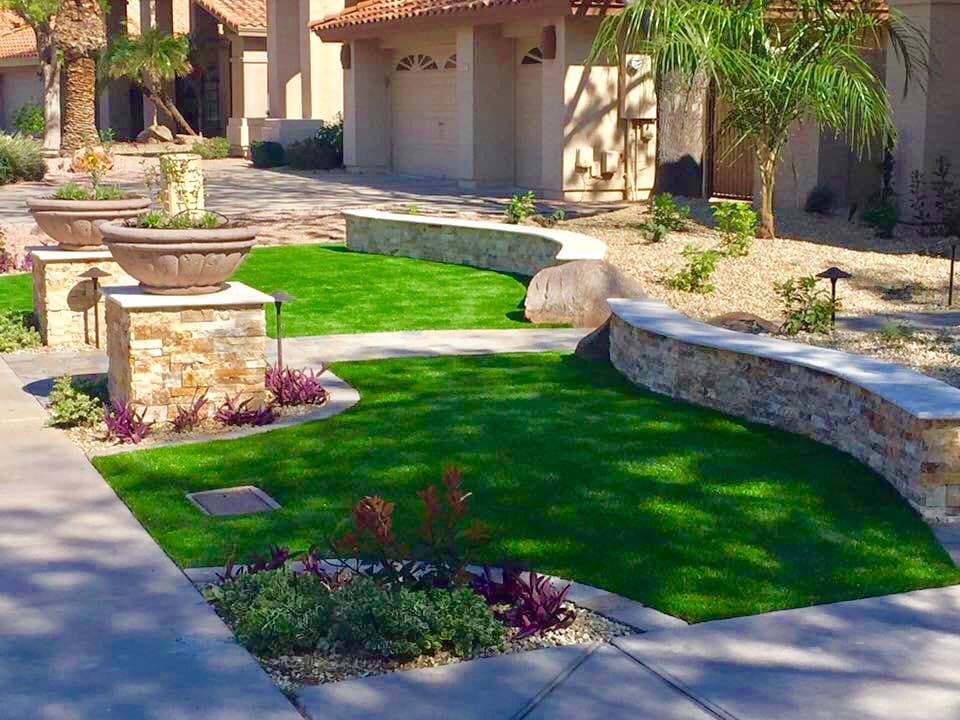 Lush landscaping featuring curved stone walls, fountains, and vibrant plants in a modern yard.