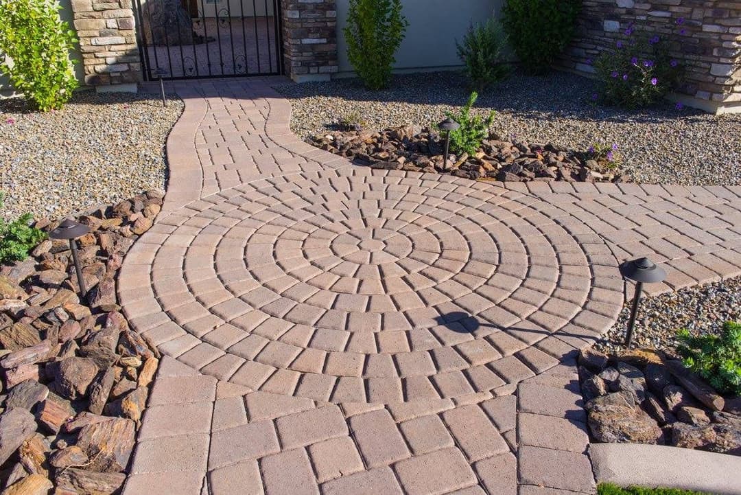 Circular stone patio design with path, surrounded by decorative rocks and garden lights.