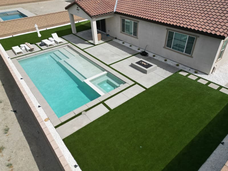 Aerial view of a modern home with pool, fire pit, and landscaped yard.