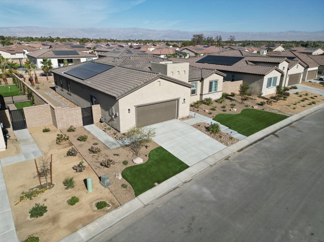 Aerial view of a modern home with solar panels in a landscaped suburban neighborhood.