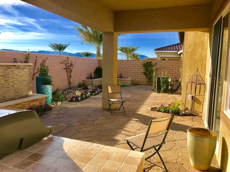Desert patio with stone flooring, potted plants, and mountains in the background.