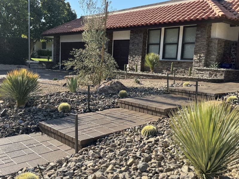 Modern desert landscaping with stone pathways, cacti, and a stylish home facade.